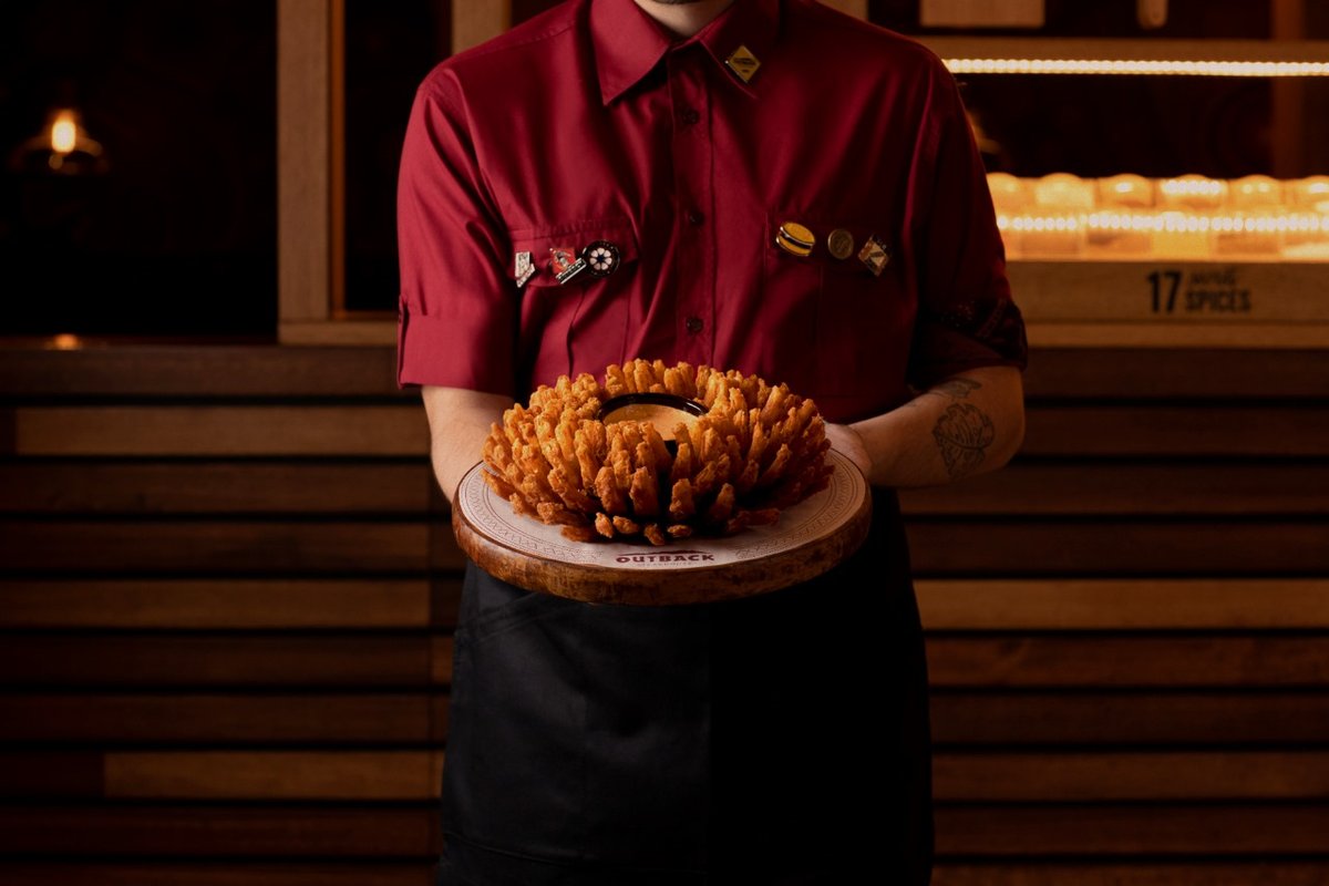 Atendente apresenta a clássica cebola empanada Bloomin' Onion, aperitivo tradicional do restaurante