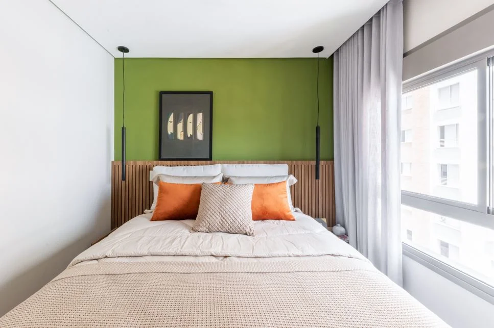 Dormitório com parede verde oliva e cabeceira ripada projetado por BMA Studio