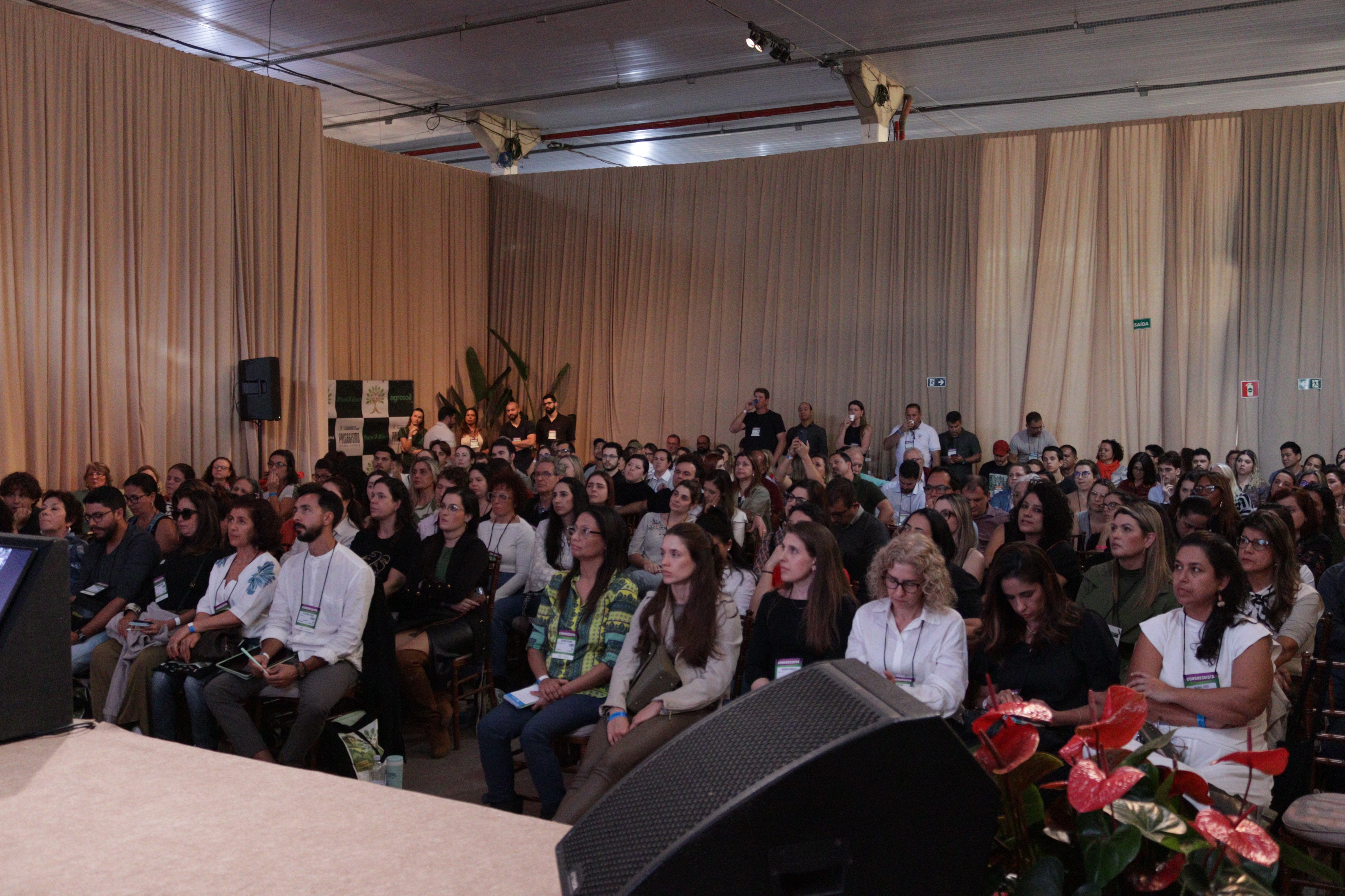 Auditório lotado com profissionais e estudantes participando das conferências do congresso.