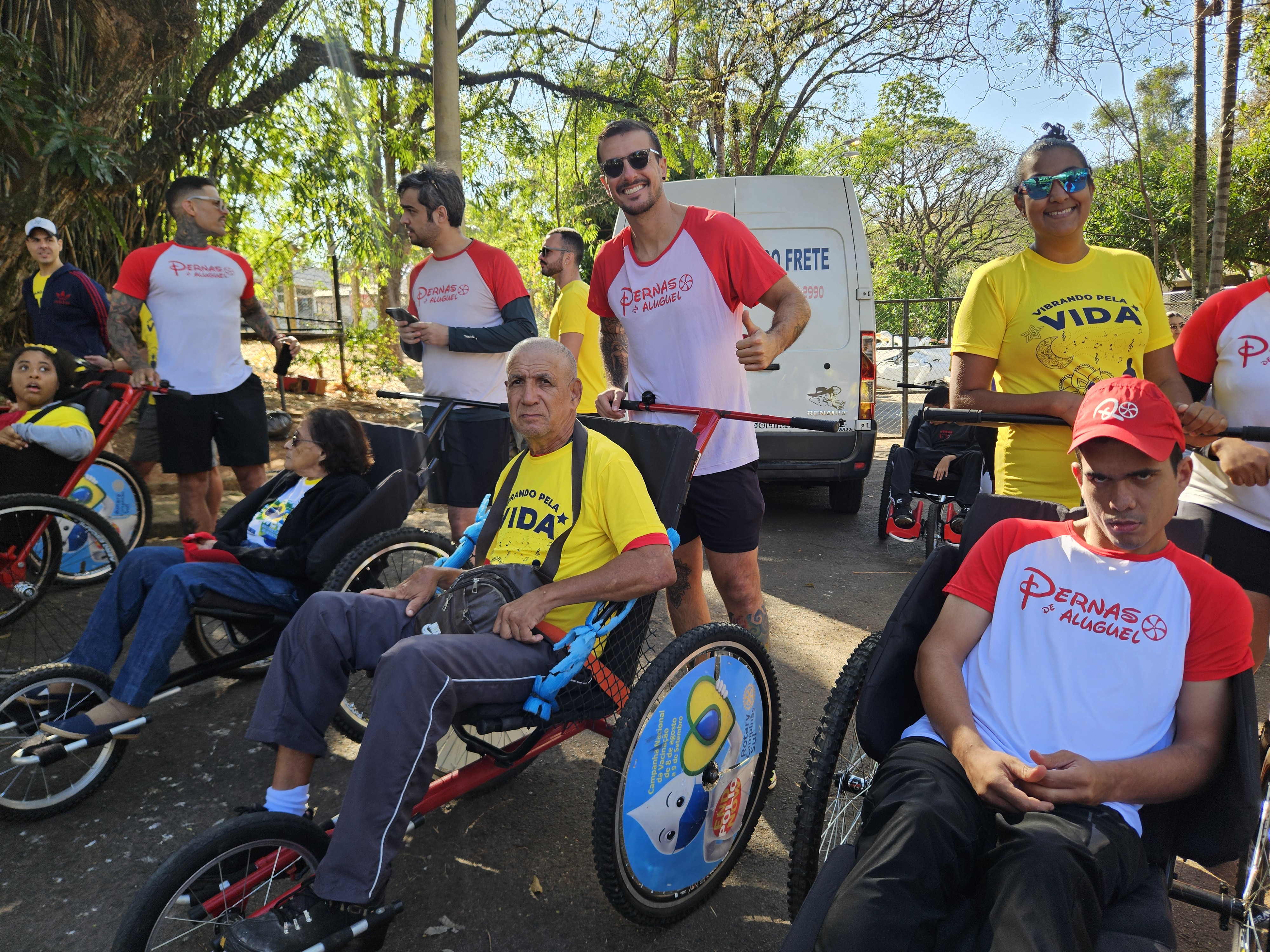 Voluntários do projeto Pernas de Aluguel e participantes em cadeiras de corrida na Lagoa do Taquaral